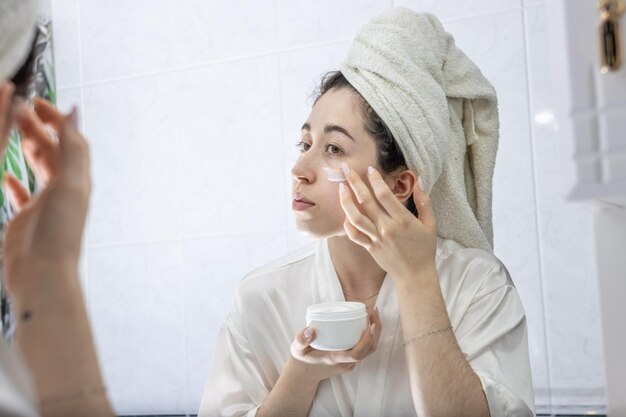 feliz-hermosa-joven-aplicando-crema-nutritiva-hidratante-colageno-piel-seca-ojos-masajeando-cara-dedos-sonriendo-concepto-tratamiento-cuidado-piel-cerrar-retrato_394312-3302